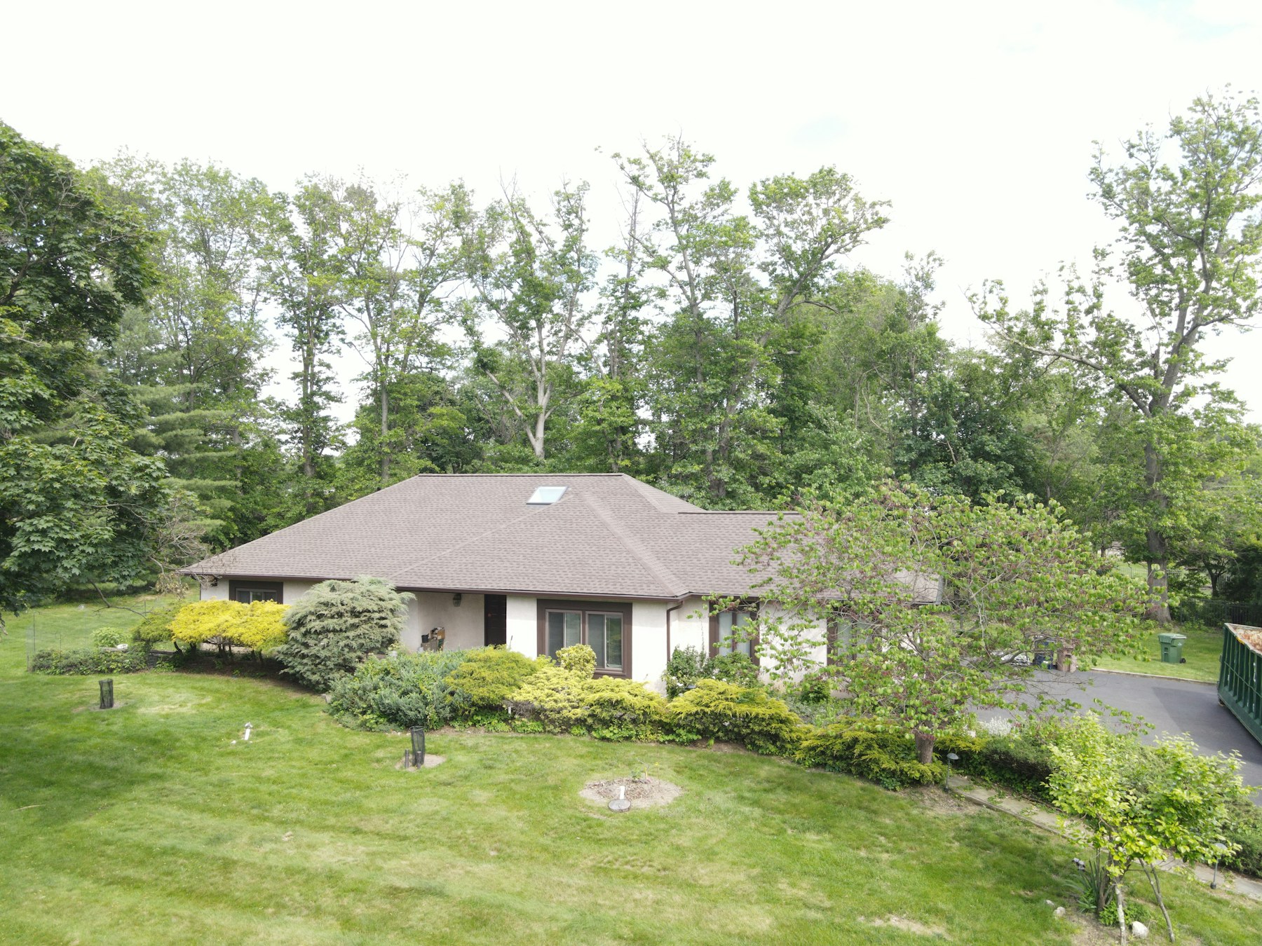 A completed roof across a single-story home framed by mature trees