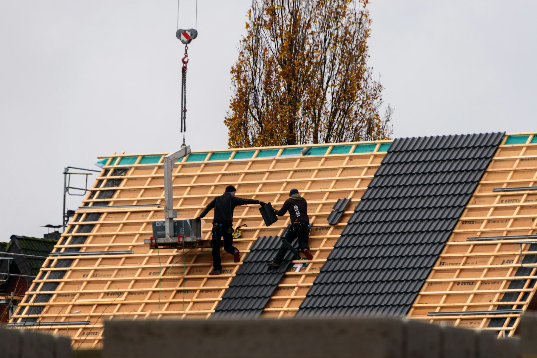 A roofing crew installing a new tile roof system across a home